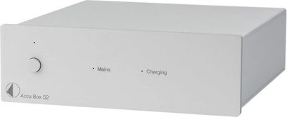 Separate power supply for HI-FI electronics Accu Box S2, rectangular silver metal casing, circular button on the left, two indicator lights, and inscriptions "Mains" and "Charging" on the front panel, shown in a slightly angled perspective view.