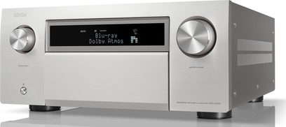 Amplificatore home cinema Denon AVC-A10H argento, vista di tre quarti, facciata con due pulsanti circolari, schermo centrale che visualizza "Blu-ray Dolby Atmos"
