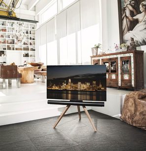 Lyst træ Spectral art AX TV-møbel på metalben med fladskærm, der viser et natligt bybillede