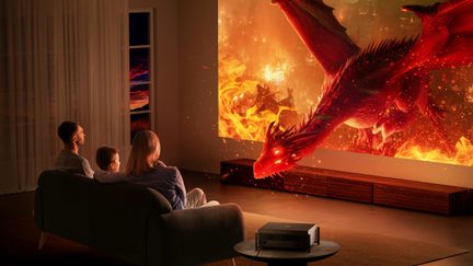 Projektor kina domowego 4K wyświetlający film o smoku na dużym ekranie w salonie, rodzina siedzi na kanapie