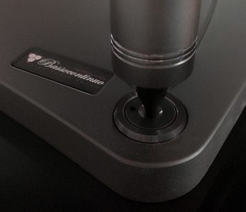 Hi-Fi nábytek Bassocontinuo Lyra 2.1 v matné černé barvě, detailní pohled z 3/4 čelní strany na horní desku s vyraženým logem a centrální nohou