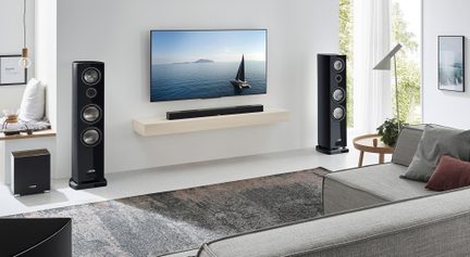 Sada domácího kina Canton s černými sloupovými reprosoustavami, soundbarem a subwooferem, instalovaná ve světlém moderním obývacím pokoji