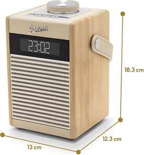 Radio til bordet Roberts Rambler Midi i cremefarvet plast med lyse træsidepaneler, perforeret metalgitter under et digitalt sort display med hvide tal og sølvfarvet logo, stor cirkulær knap i børstet aluminium på toppen og tilpasset sidehåndtag, set fra højre forfra i trekvarts vinkel