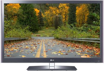 LG 55LW5500-fjernsyn, der viser en skovvej om efteråret med orange, faldne blade og træer langs vejkanten