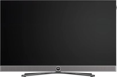 Telewizor Loewe Vega 43 czarny, widok z przodu, duży płaski ekran z szarym soundbarem i centralną zakrzywioną podstawą