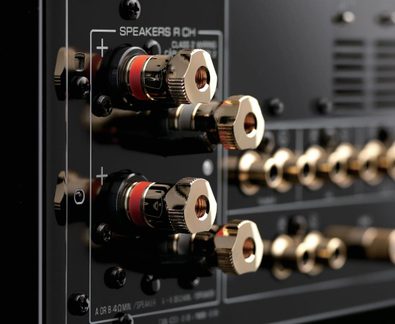 Gold-plated speaker terminals on black hi-fi amplifier rear panel, close-up of audio connectors