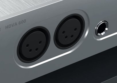 Hovedtelefon-forstærker HDVA 600 i grå metallic, tæt forfra-billede af de to jackstik og det runde, forkromede logo