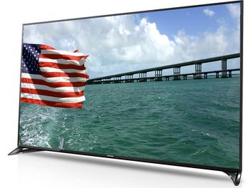 Panasonic TX-65CX800 65-inch TV displaying an American flag waving in front of a multi-span bridge over water