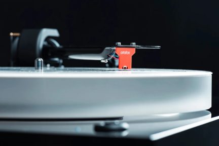Hvit vinylplatespiller med rød Ortofon-pickup og tonearm i nærbilde
