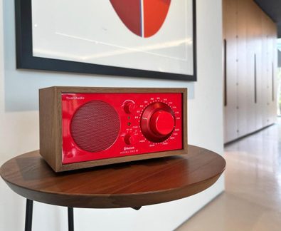 Radio in legno da tavolo, fronte rosso, griglia a sinistra e grande manopola di regolazione a destra, vista a tre quarti