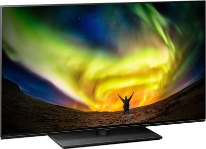 Panasonic TX-48LZ980E-fladskærm, der viser et grønt og gult nordlys over et øde, bjergigt landskab med en menneskelig silhuet i midten