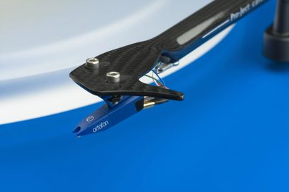 Ortofon přenoska na vinylové desky na modrém raménku s nastavovacím šroubem, detailní boční pohled