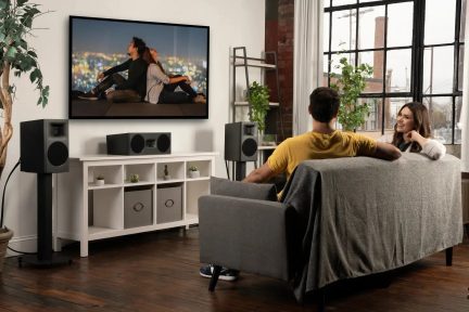 Diffusori home cinema neri con diffusore centrale sotto televisore a parete in un soggiorno moderno