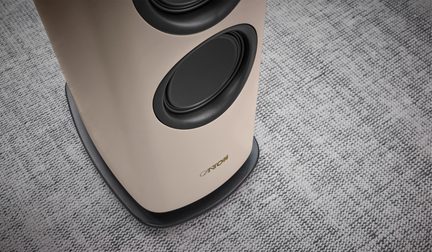 Beige Canton-Standlautsprecher mit seitlichen schwarzen Woofern, schwarzem ovalem Standfuß auf grauem Teppich