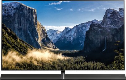 Panasonic TX-65EZ1000E-fladskærm, der viser en bjergdal med stejle klipper, skove og en skyet himmel