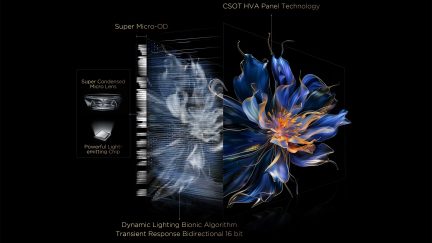 Painel de vidro preto, corte lateral em três quartos expondo uma matriz de microlentes translúcidas e chip luminoso interno, fachada exibindo uma flor digital azul royal e laranja