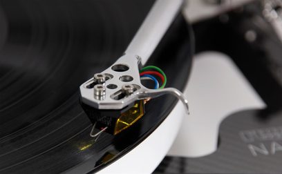 Giradischi hi-fi Rega Naia con testina Aphelion 2 MC, vista ravvicinata sul braccio di lettura argentato e sulla testina nera e gialla