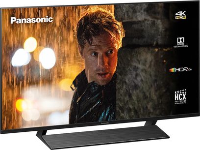 Panasonic TX-58GX800E 4K HDR10+ tv set forfra i mørke omgivelser, tændt skærm viser en mands ansigt