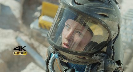 Nærbillede af en kvindelig astronauts ansigt med et astronauthjelm på, hvor der er et spejlbillede i visiren