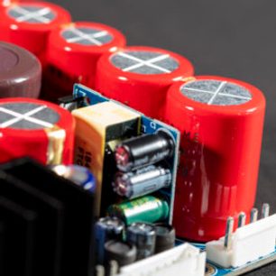 Røde elektrolytiske kondensatorer og grønne printplader i et åbent sort elektronisk kabinet