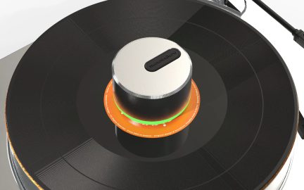Sort og sølvfarvet HumminGuru-pladevæg t med grøn ring i midten af en vinylplade på en pladespiller
