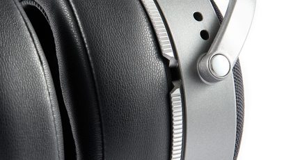 Seitliche Nahaufnahme des schwarzen Kunstleder-Ohrpolsters, des silbernen gerändelten Rings und des gelochten Aluminiumgelenks des Audeze LCD-S20 Kopfhörers