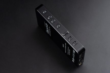 Amplificator portabil pentru căști audio, negru, dreptunghiular, cu butoane laterale argintii pe fundal negru
