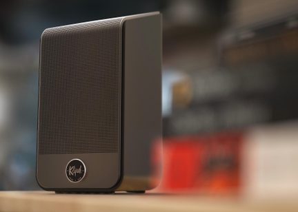 Kompaktní černý stolní reproduktor Klipsch s kovovou mřížkou na čelní straně, zobrazený z pohledu ze tří čtvrtin