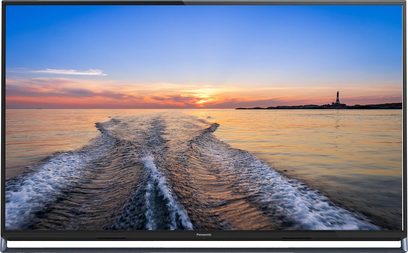 Panasonic TX-65AX800E-fladskærm, der viser en solnedgang over et roligt hav med kølevandet fra en båd i forgrunden
