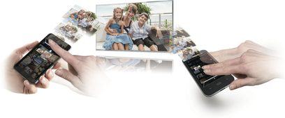 Televizor Panasonic TX-P50VT60E zobrazující fotografii tří usmívajících se dívek sedících, držený dvěma rukama se smartphony