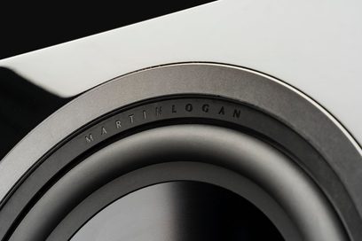 MartinLogan Dynamo 12 subwoofer, nærbillede af en sort, cirkulær højttaler med grå kant og synlig inskription