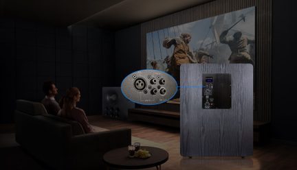 Šedý domácí kino subwoofer se zadním zesíleným panelem a detailními audio konektory v tmavém obývacím pokoji