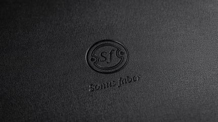 Detailní záběr na logo Sonus faber vyražené na černém texturovaném povrchu