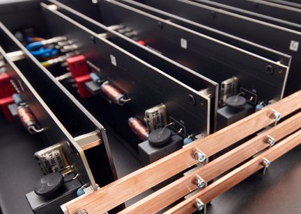 Nahaufnahme mehrerer schwarzer elektronische Platinen, die vertikal ausgerichtet sind, mit befestigten Komponenten und Kupferschienen