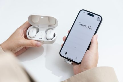 Auricolari wireless Bose bianchi nella custodia di ricarica, davanti a uno smartphone nero con app audio Questyle