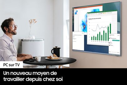 Telewizor Samsung QE65Q80B 2022 wyświetlający kolorową grafikę, stojący na okrągłym czarnym stoliku przed uśmiechniętym mężczyzną