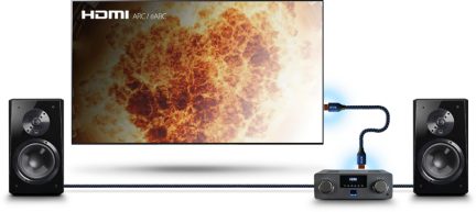 Sistema de cine en casa con dos altavoces negros, un amplificador negro y una pantalla que muestra una explosión de fuego naranja