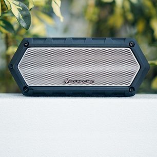 Trådløs tilsluttet højttaler Soundcast VG1 sort, set forfra, rektangulært metalnet, grønne blade i baggrunden