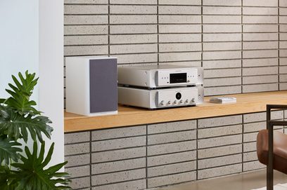 CD-програвач Marantz CD60 сріблястого кольору та інтегрований підсилювач, розташовані на дерев'яній полиці перед стіною зі світлої цегли