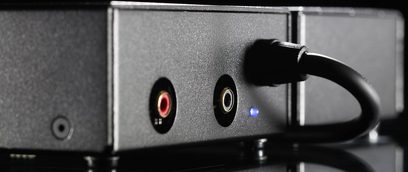 Передпідсилювач фонокоректора Lehmann Audio Black Cube SE чорного кольору, вид спереду зблизька, 2 роз'єми RCA (червоний і білий), синій LED-індикатор увімкнено