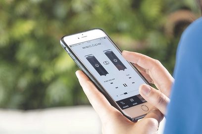 Trådløs Bluetooth-højttaler Escape P9 i sort holdt i en hånd mod en baggrund af vegetation, skærmen viser knapper til lydafspilning