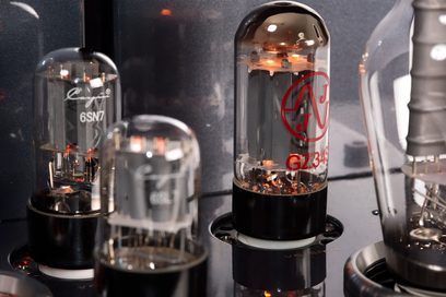 Vista oblíqua aproximada do chassi metálico preto do Cayin CS-300A com várias válvulas de vidro incandescentes com bases pretas