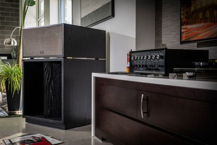 Diffusore acustico nero in legno e amplificatore audio nero in una cucina moderna con mobili in legno scuro