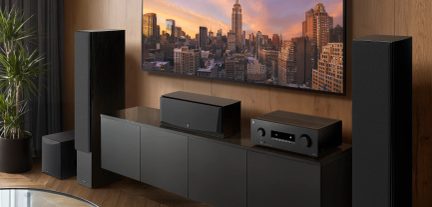 Svart hjemmekinoanlegg med gulvhøyttalere, senterhøyttaler, subwoofer og AV-forsterker under TV-en