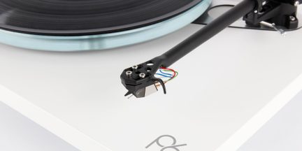 Braccio di platino nero con cavi colorati, piatto vinile nero, base bianca, vista in primo piano