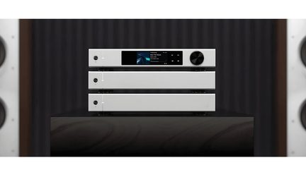 Set van drie hi-fi-modules in geborsteld zilverkleurig aluminium, frontaal gezien; de bovenste behuizing heeft een centraal kleurenscherm en een grote zwarte draaiknop rechts, terwijl de twee onderste behuizingen elk een enkele ronde knop links hebben.
