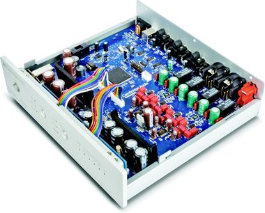 Blå printplade med forskellige elektroniske komponenter i en åben metalkabinetboks, set ovenfra i et skråt perspektiv