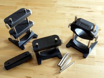 Five black plastic cable ties of various sizes, disassembled and arranged on a light wooden surface