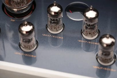 Nærbillede set ovenfra af den blågrå metalliske topplade på Cayin CS-55A EL34, der viser fire 12AX7/ECC83-glasrør med kromhætte, isat sorte fatninger
