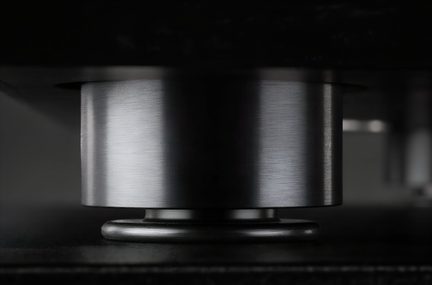 Pied de meuble cylindrique en métal brossé gris anthracite, vue de profil sous un meuble noir